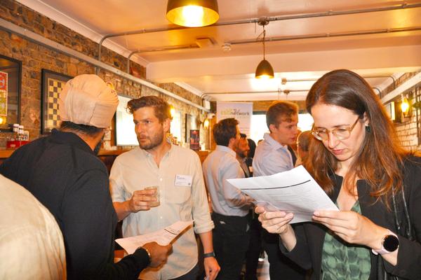 A guest reading the printed attendee list with a coffee in hand